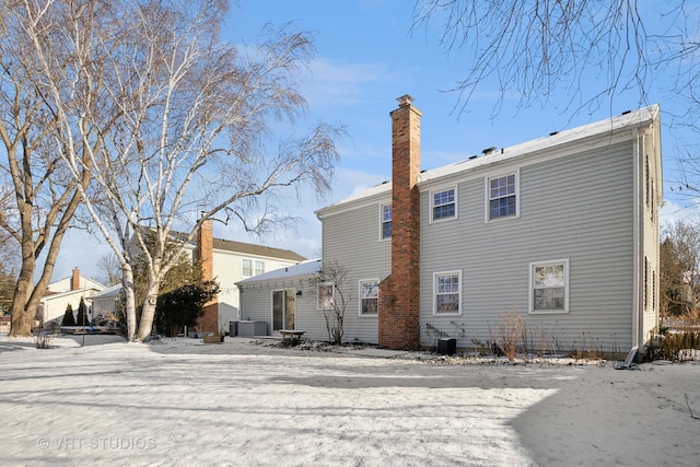 snow covered house featuring central air condition unit