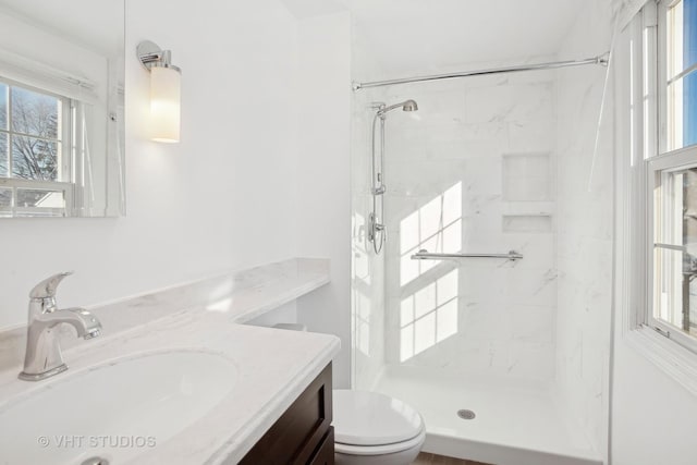 bathroom featuring toilet, vanity, and a tile shower