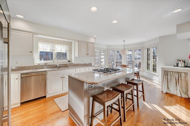 kitchen featuring sink, hanging light fixtures, a kitchen island, stainless steel appliances, and white cabinets