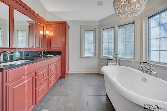 bathroom with tile patterned flooring, vanity, a chandelier, and a bathing tub