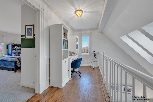 office with ornamental molding, vaulted ceiling with skylight, and light hardwood / wood-style floors