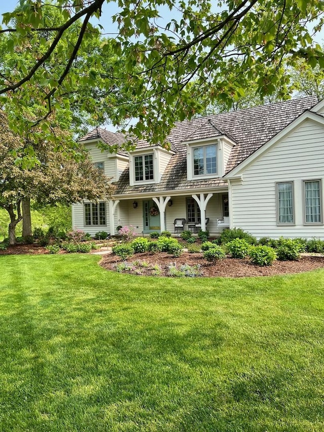 rear view of property featuring a yard and covered porch