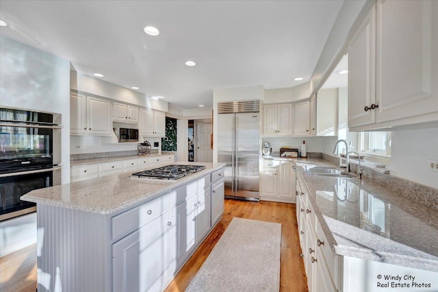 kitchen with appliances with stainless steel finishes, sink, a kitchen island, and white cabinets