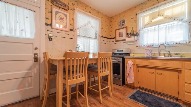 kitchen with stainless steel range, light hardwood / wood-style floors, and sink