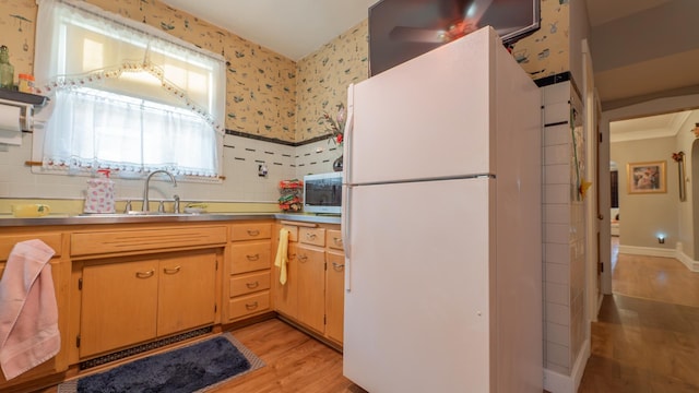 kitchen featuring light wood-type flooring, white fridge, and sink