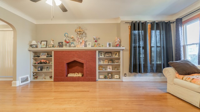 living room featuring hardwood / wood-style flooring, a brick fireplace, ceiling fan, and ornamental molding