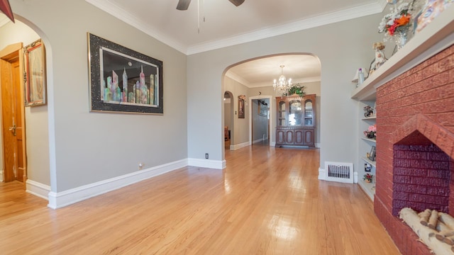 entrance foyer with ceiling fan with notable chandelier, light hardwood / wood-style floors, crown molding, and a fireplace