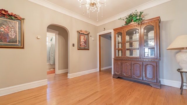 hallway with a chandelier, light hardwood / wood-style floors, and ornamental molding