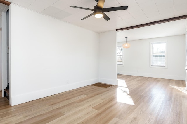 spare room featuring beam ceiling, light wood-type flooring, and ceiling fan