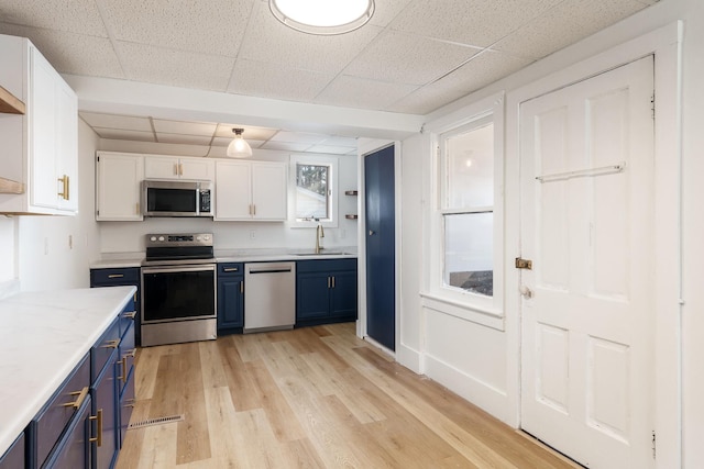 kitchen featuring white cabinets, appliances with stainless steel finishes, blue cabinetry, and sink