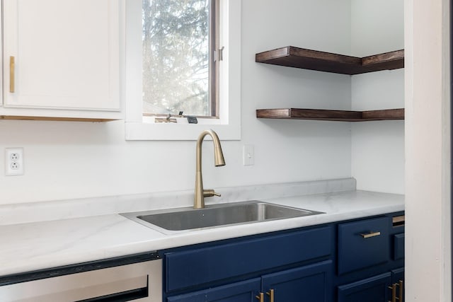 kitchen with white cabinets, blue cabinets, sink, wine cooler, and light stone countertops