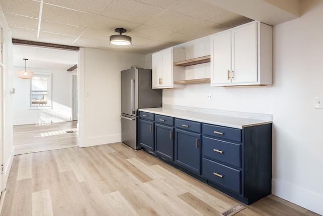 kitchen with white cabinets, light hardwood / wood-style floors, blue cabinetry, and stainless steel refrigerator