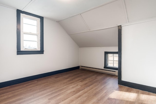 bonus room with a wealth of natural light, hardwood / wood-style floors, lofted ceiling, and a baseboard heating unit