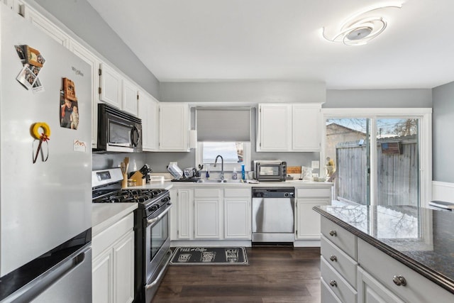 kitchen with sink, dark wood-type flooring, appliances with stainless steel finishes, and white cabinetry