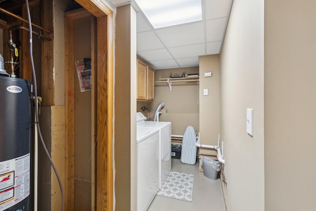 washroom with water heater, washer and dryer, and cabinets