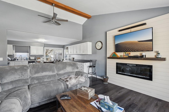 living room featuring sink, ceiling fan, a large fireplace, dark hardwood / wood-style floors, and lofted ceiling with beams