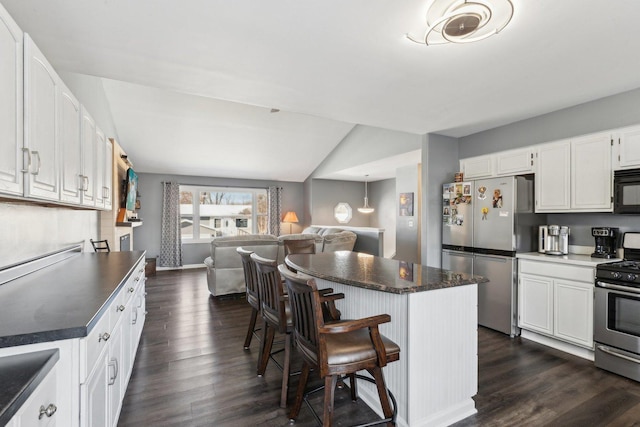 kitchen featuring white cabinetry, lofted ceiling, a kitchen island, dark hardwood / wood-style flooring, and appliances with stainless steel finishes