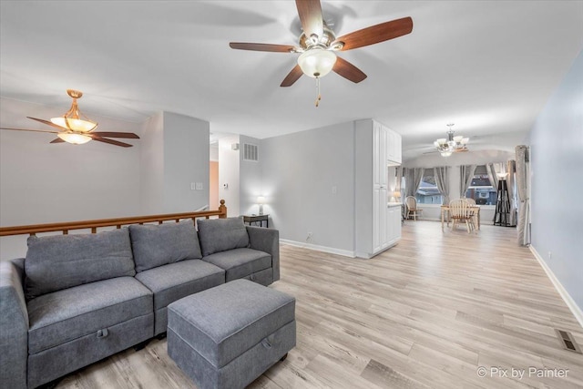 living room with ceiling fan with notable chandelier and light hardwood / wood-style flooring