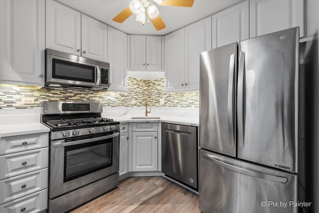 kitchen featuring appliances with stainless steel finishes, sink, white cabinets, and decorative backsplash