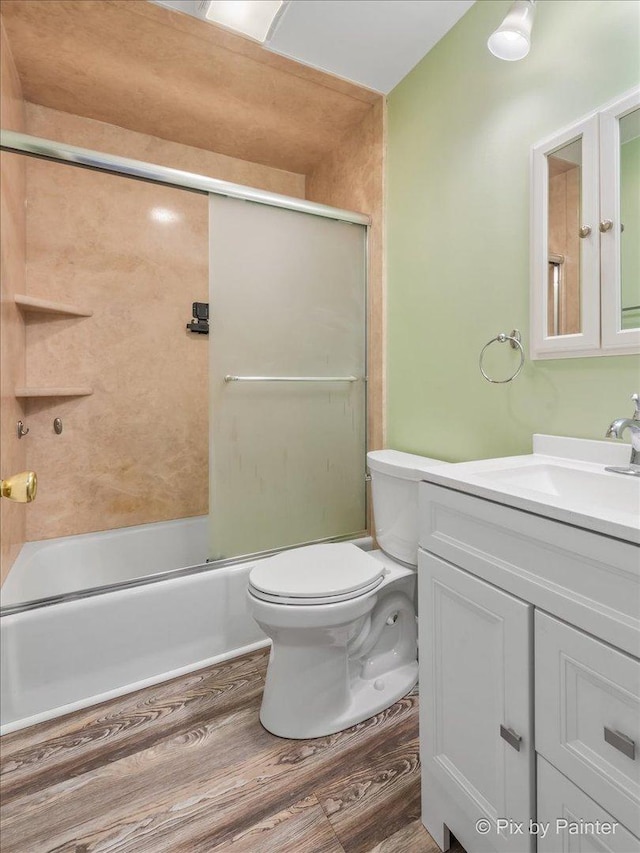 full bathroom featuring vanity, hardwood / wood-style flooring, enclosed tub / shower combo, and toilet