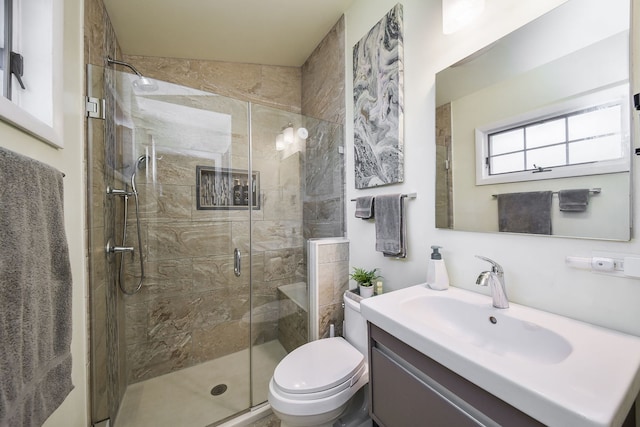 bathroom featuring vanity, a shower with shower door, and toilet