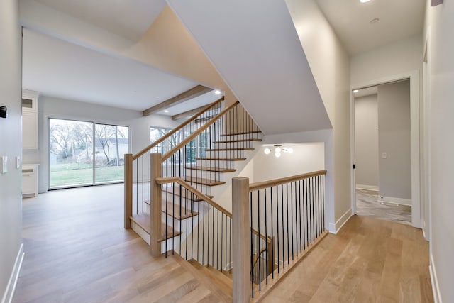 stairs featuring beamed ceiling and hardwood / wood-style flooring