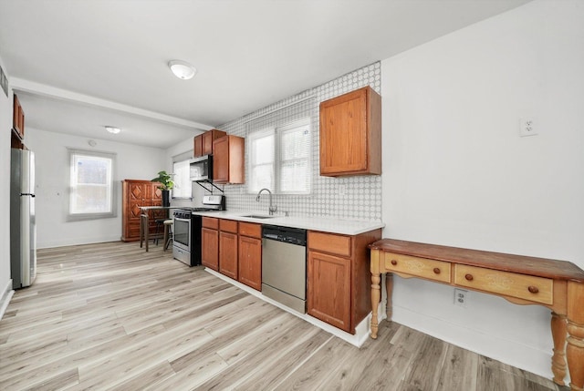 kitchen featuring appliances with stainless steel finishes, light wood-type flooring, tasteful backsplash, and sink