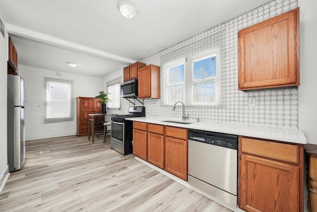 kitchen with decorative backsplash, sink, stainless steel appliances, and light wood-type flooring