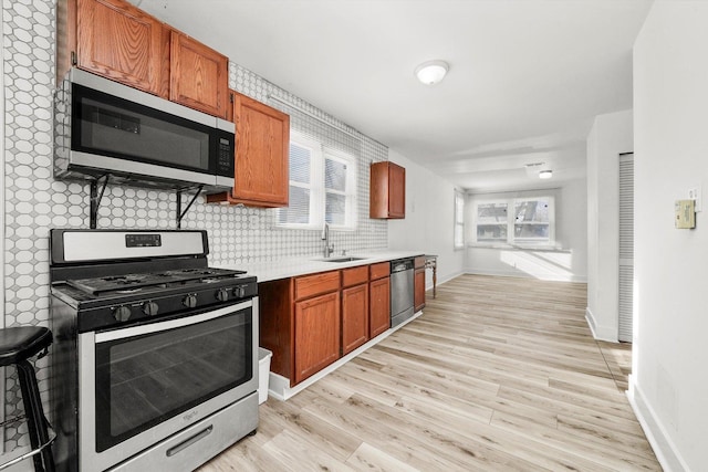 kitchen with backsplash, sink, stainless steel appliances, and light hardwood / wood-style floors