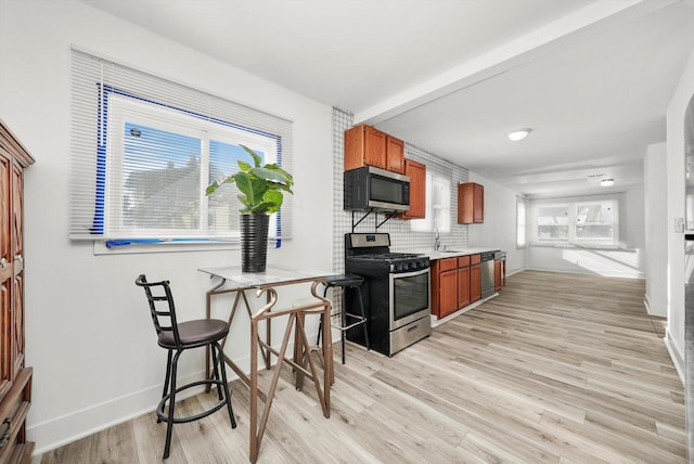 kitchen with light hardwood / wood-style flooring, sink, stainless steel appliances, and tasteful backsplash