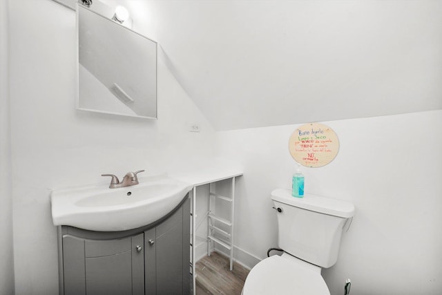 bathroom with vanity, toilet, wood-type flooring, and lofted ceiling