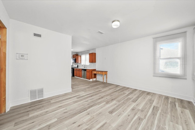 unfurnished living room featuring sink and light hardwood / wood-style floors