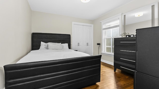 bedroom with dark hardwood / wood-style flooring and a closet