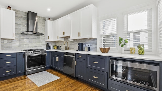 kitchen featuring white cabinets, wall chimney exhaust hood, sink, and stainless steel appliances