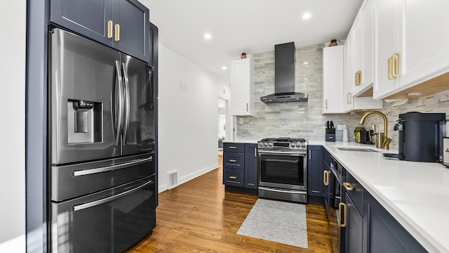 kitchen featuring white cabinetry, sink, stainless steel appliances, wall chimney range hood, and backsplash