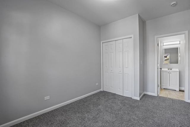 unfurnished bedroom with carpet flooring, ensuite bath, and a closet