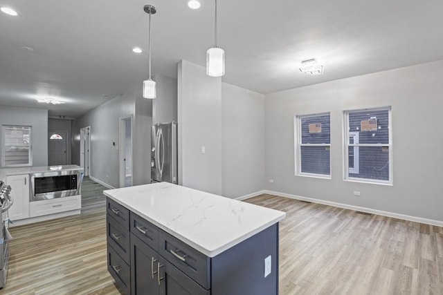 kitchen with a center island, stainless steel appliances, decorative light fixtures, and light wood-type flooring