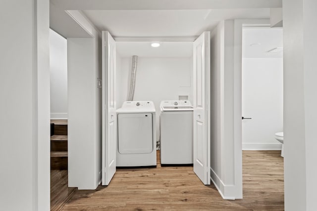 laundry room featuring independent washer and dryer and light hardwood / wood-style flooring