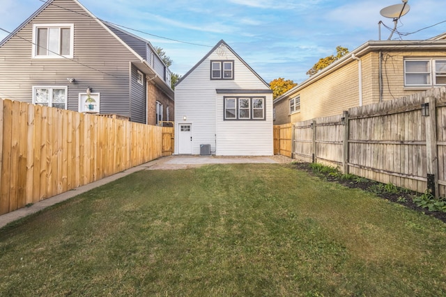 rear view of house featuring central AC unit and a yard