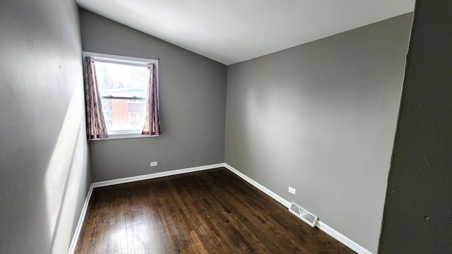 spare room with vaulted ceiling and dark wood-type flooring