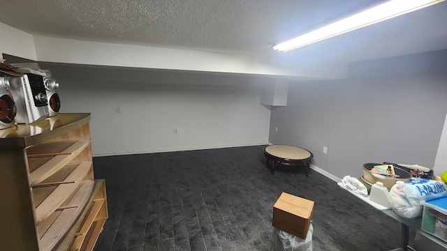 basement with dark wood-type flooring and a textured ceiling