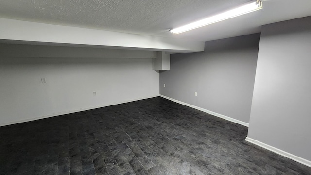 basement featuring dark hardwood / wood-style floors and a textured ceiling