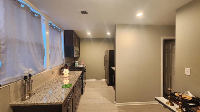 kitchen with light stone counters, dark brown cabinetry, and appliances with stainless steel finishes