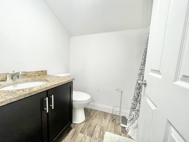 bathroom with vanity, lofted ceiling, wood-type flooring, and toilet