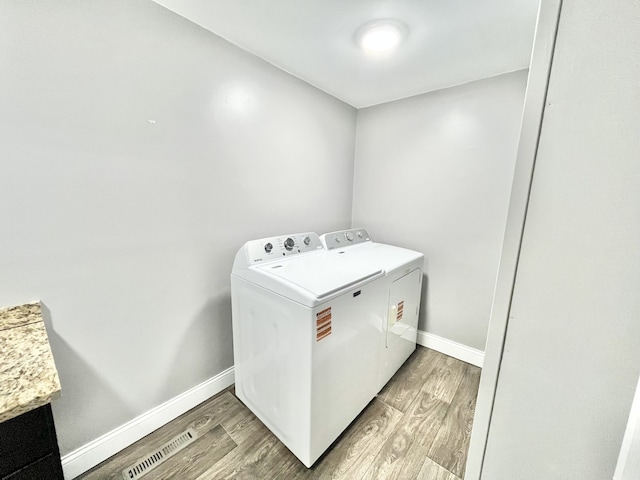 clothes washing area with separate washer and dryer and light hardwood / wood-style floors