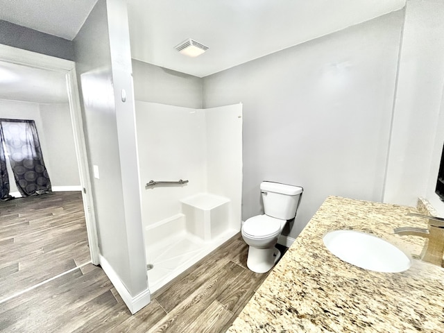 bathroom with walk in shower, vanity, toilet, and hardwood / wood-style floors