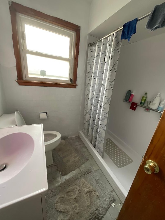 bathroom featuring a shower with shower curtain, vanity, toilet, and tile walls