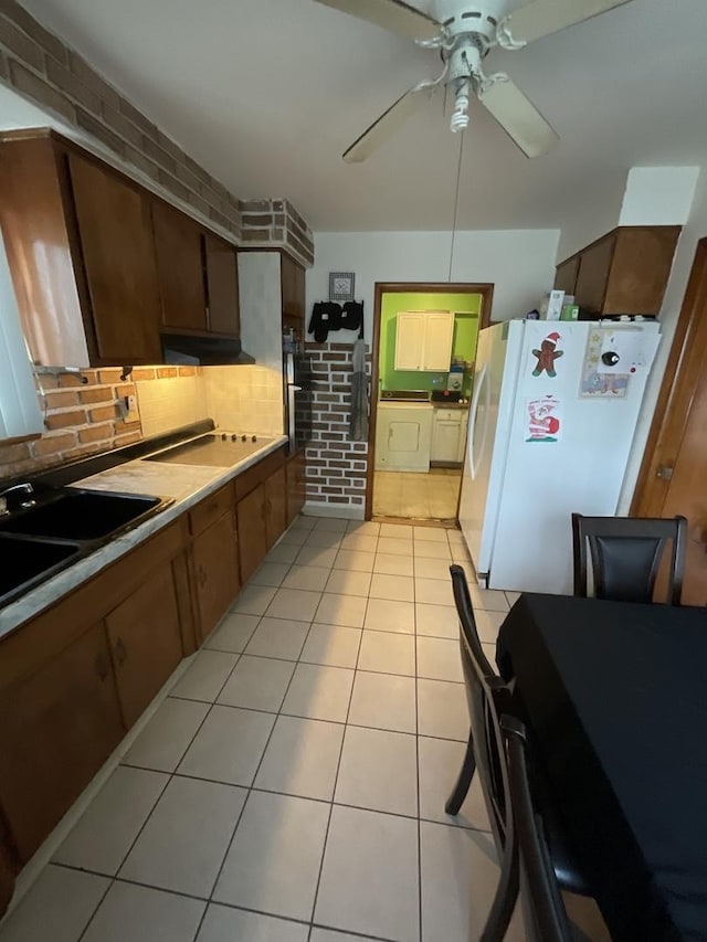 kitchen featuring backsplash, brick wall, ceiling fan, light tile patterned floors, and white fridge