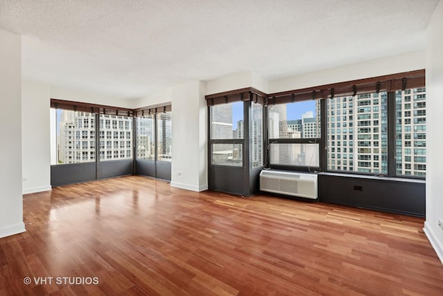 empty room featuring hardwood / wood-style flooring, a healthy amount of sunlight, and a textured ceiling