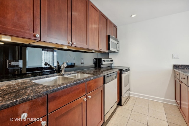 kitchen with sink, light tile patterned floors, dark stone counters, and appliances with stainless steel finishes